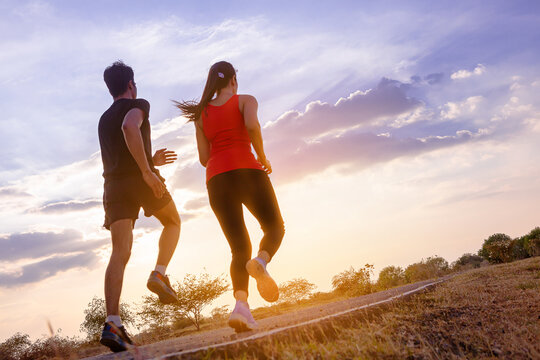 Silhouette of couple running together on road with sunset background.. Couple, fit runners fitness runners jogging together during outdoor workout