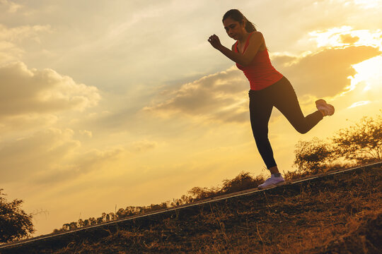 Silhouette of young woman running sprinting on road. Fit runner fitness runner during outdoor workout with sunset background. Selected focus