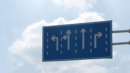Road Sign with Lane Direction Arrows Against Blue Sky © Jingjing Song