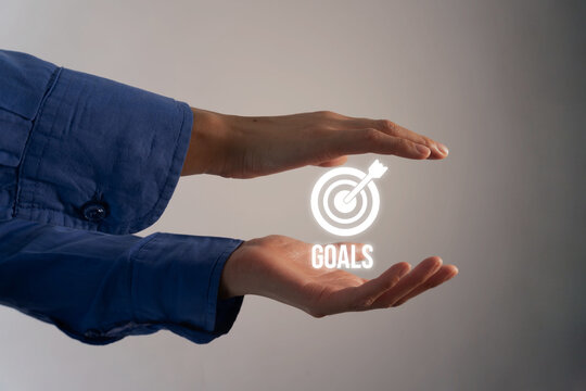 Cupped hands hold floating goal icon symbolizing achievement and ambition