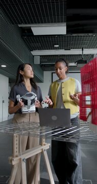 Two Businesswomen Collaborating in Modern Office Space, using Laptop and VR headset