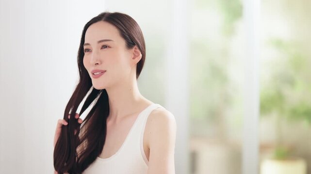 明るい部屋の中でヘアケアをする日本人女性