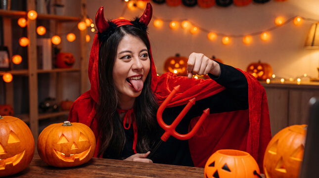 A person in a devil costume playfully poses at a festive Halloween holiday party, adding fun spooky autumn October celebration energy for seasonal marketing.