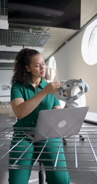 Young Adult Woman Focusing on Laptop in Modern Open plan Workspace, using VR headset