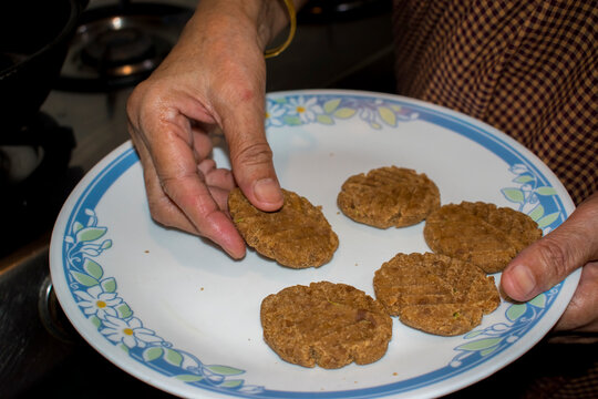 old lady hand holding raw wheat thekua for frying, bihari festival prasad making.