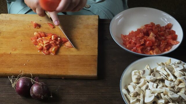A woman's hands cut fresh red tomatoes with a knife on a cutting board