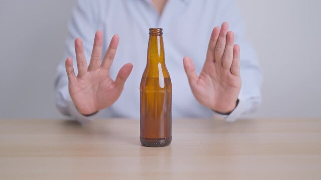 man making stop hand gesture to refuse a bottle of Beer, Healthy man say no to alcohol drink, stop alcoholism and addiction concept. Responsible man reject a drink before driving and quit booze