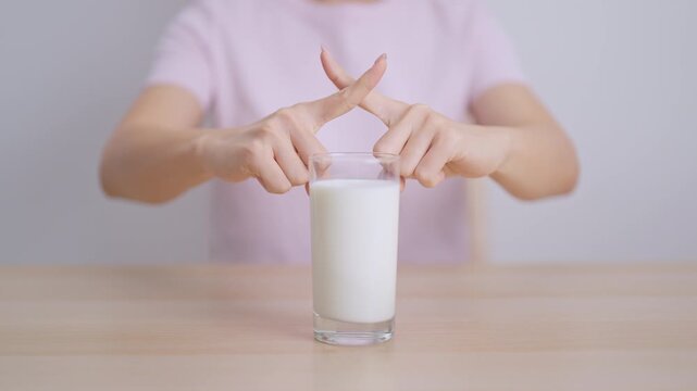 Lactose intolerance and Milk allergy. woman hand stop and refuse Milk, having abdominal cramps and pain when drink Cow Milk. Symptom stomach ache, Dairy intolerant, Nausea, Bloating, Gas and Diarrhea