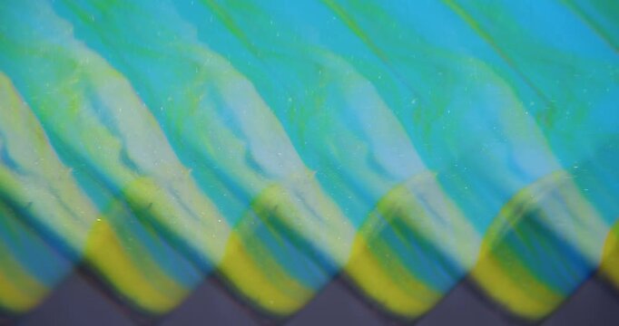 Shimmer ink. Blur shiny fluid. Neon blue yellow color glimmer mix sparkling texture floating on abstract bright art background.