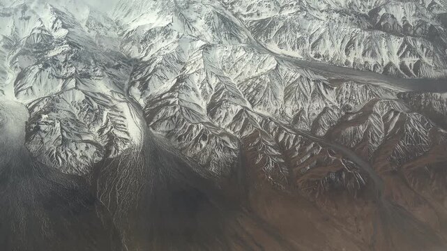 Stunning window seat view of massive snow-covered mountain ranges in Northwest China during a flight. 