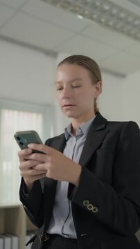 Businesswoman using smartphone for messaging in office