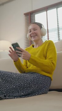 Joyful woman with headphones listening to music and using smartphone