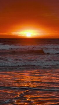 Sunset Over the Sea and Beach with Glowing Orange Sky, Calm Ocean Waves, Cloudy Horizon, Golden Sunlight, and Peaceful Coastal Landscape at Evening Dusk