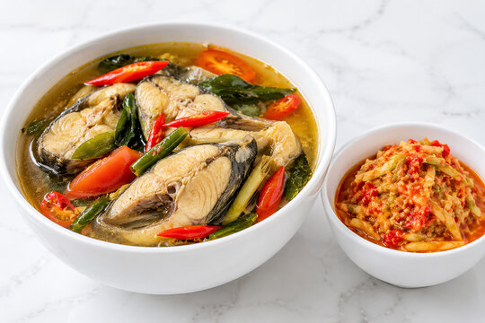 Close-up of Indonesian fish broth (Pindang Ikan) in a white bowl on a marble background