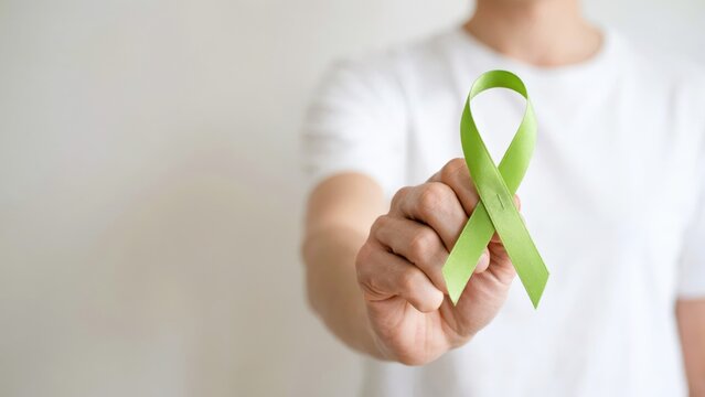 Person holding a lime green awareness ribbon isolated on white background