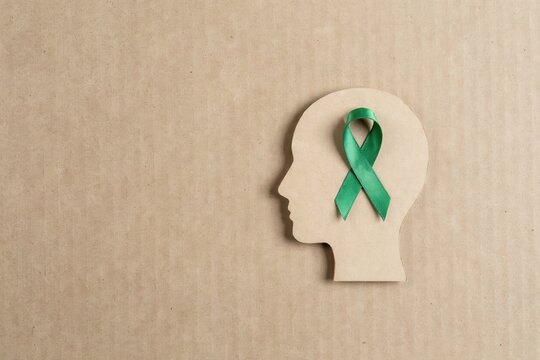 Cardboard human head silhouette with a green awareness ribbon for mental health support