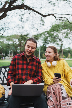 Young couple enjoying remote work outdoors in park