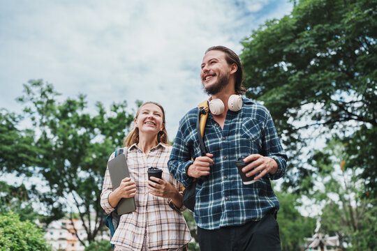 Happy students walking outdoors on campus with coffee