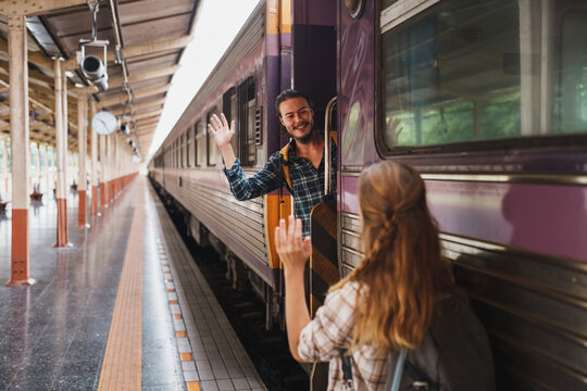 Couple waving goodbye at train station platform