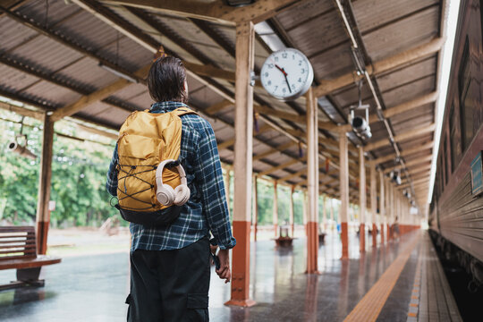 Man traveling carrying backpack waiting for train at station