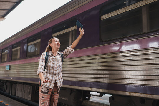 Woman waving passport traveling by train