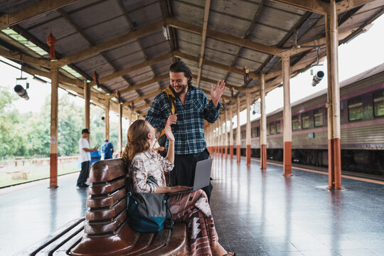 Digital nomads waving greeting at train station platform