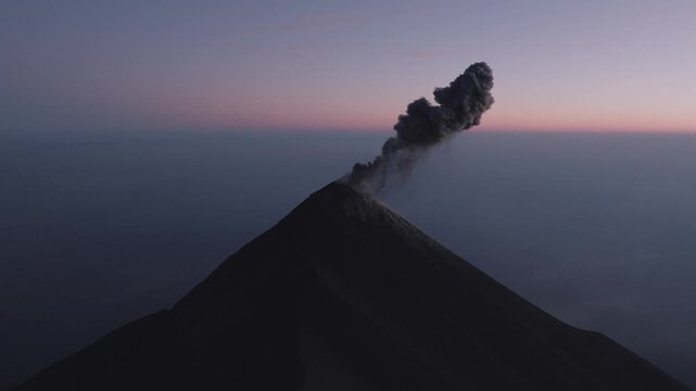 Aerial footage captures Volc&aacute;n de Fuego erupting at dawn in Guatemala, with dramatic ash plumes rising into the colorful sky.
