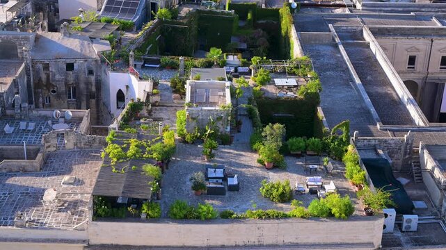 Lush rooftop garden terraces with seating areas sit atop old stone buildings in the historic center of Lecce.