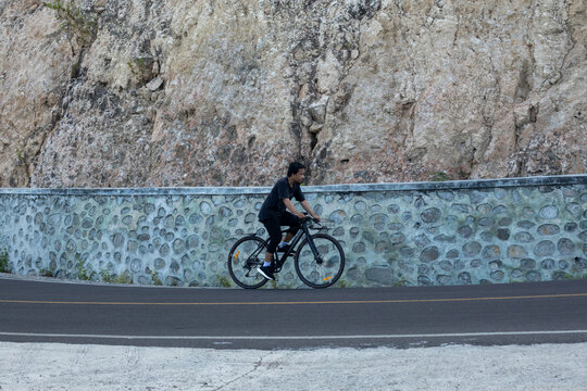 Man Cycling Along a Stone Wall Road