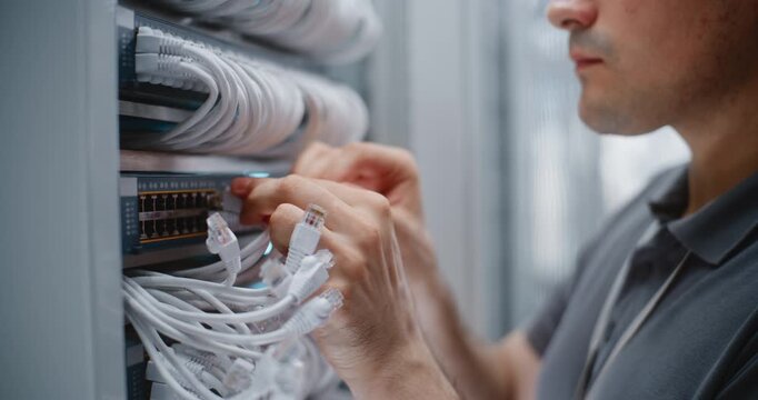 Male Data Center Technician Checks Structured Cabling Connections and Repositions Ethernet Patch Cords, Keeping Rack Wiring Organized For Efficient Maintenance, Connectivity and Network Service.