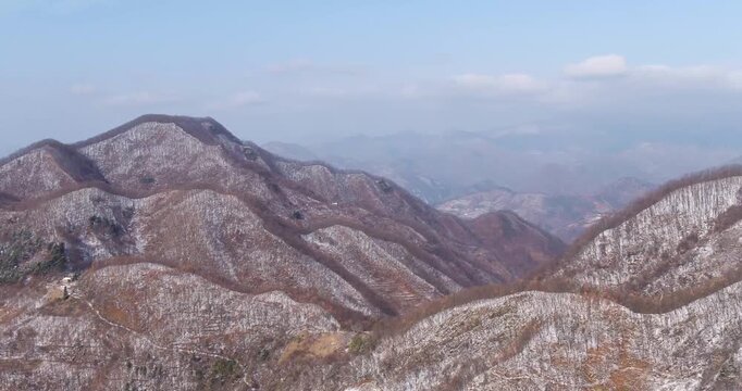 Qinling Mountains winter snowscape aerial view with bare deciduous forests and layered ridges under clear sky