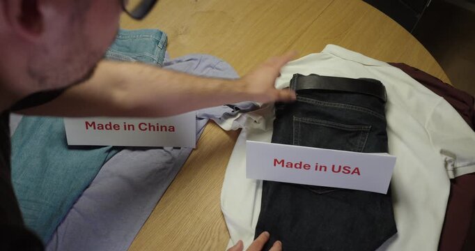 Person comparing the quality of Made in USA and Made in China clothing by inspecting denim fabric, material and workmanship. Concept of product quality, country of origin and global manufacturing.