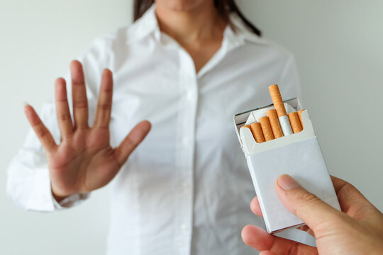 A person making a stop gesture to refuse a pack of cigarettes being offered, representing quitting smoking, health awareness, addiction recovery, and willpower. concept medical