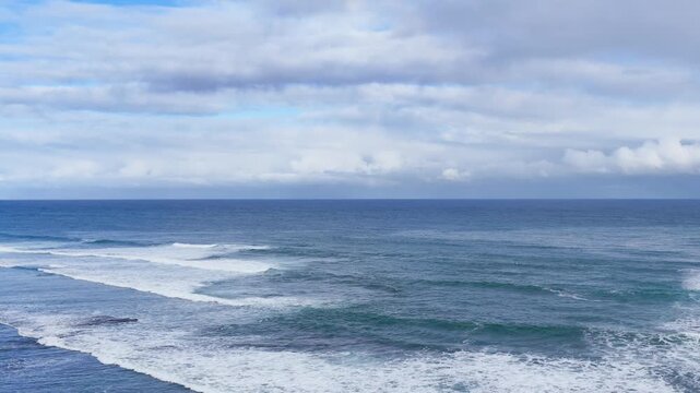 Ocean Waves Rolling Towards Shore Under Cloudy Blue Sky