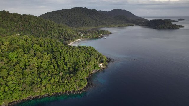Aerial view of the forested tropical coastline and coral reef-fringed waters of Weh Island, Aceh, Indonesia.