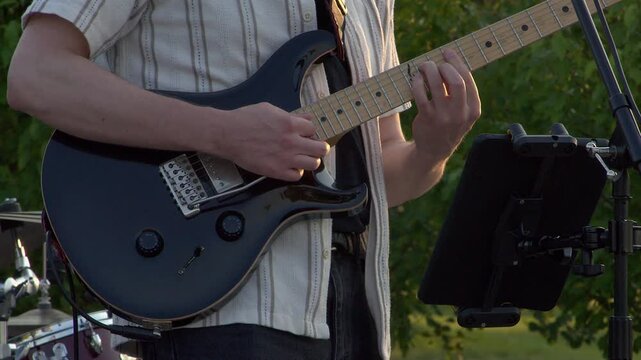 At outdoor gig, guitarist plays black electric guitar with whammy bar