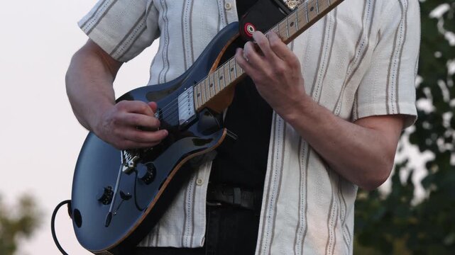 Male guitarist plays solo on electric guitar at outdoor performance
