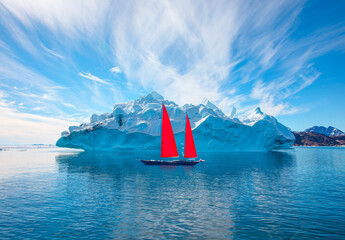 Giant iceberg near Kulusuk with lone yacht with red sails - Greenland, East Greenland © muratart