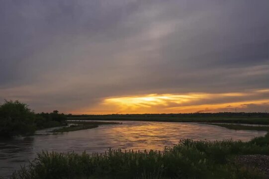 Wide river at sunset with golden火烧云 clouds reflecting on water, Xinjiang Ili River valley natural landscape