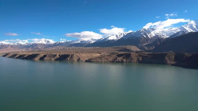 Aerial view of白沙湖 (Bai Sha Lake) in Pamir Plateau, Xinjiang, with snow-capped mountains and turquoise water under clear blue sky