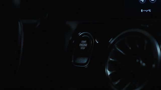 Hand pressing engine start button inside vehicle dashboard