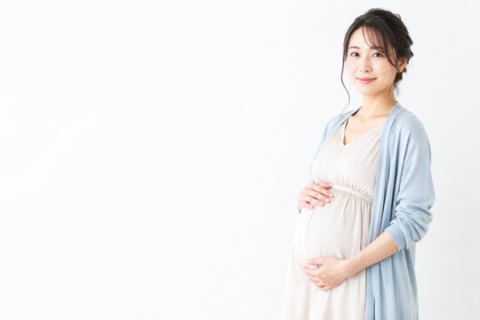 白背景でお腹を抱えて微笑む日本人妊婦