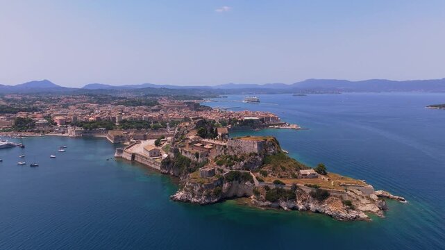 Drone video flying towards the historic Old Venetian Fortress and the old town of Corfu surrounded by the Ionian Sea.
