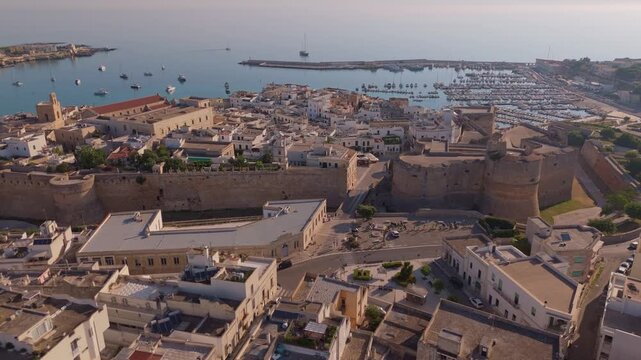 Drone footage flying over the historic buildings of Otranto revealing the port and calm sea in the background.