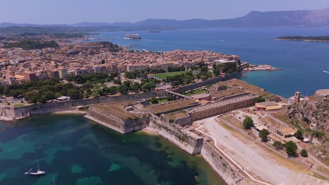 Drone tracking shot flying past the Old Venetian Fortress revealing the historic city center of Corfu and the coastline.