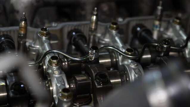 A close-up view highlights fuel rail tubes and fuel injectors installed on the open cylinder head of a car engine.