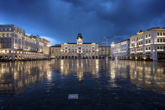 Illuminated square Piazza Unit&agrave; d'Italia, Town Hall, Palazzo Communale, with reflection, dramatic clouds, blue hour, old town, Trieste, Friuli-Venezia Giulia region, Italy