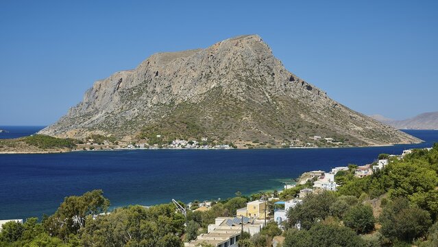 Massouri, a mountain rising above a blue bay accompanied by a small coastal village, Kalymnos, Sponge Diver Island, Dodecanese, Greek Islands, Greece