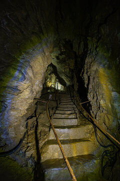 Narrow stone stairs and metal handrails leading through an illuminated limestone passage inside the Lurgrotte Peggau cave system in Styria, Austria