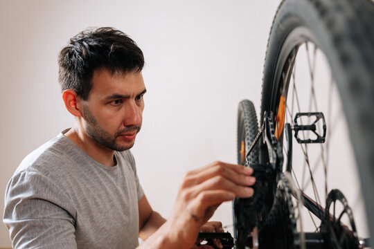 DIY bicycle maintenance at home. Close-up of man fixing bike. Hobby and active lifestyle concept. Shallow depth of field, neutral color palette.